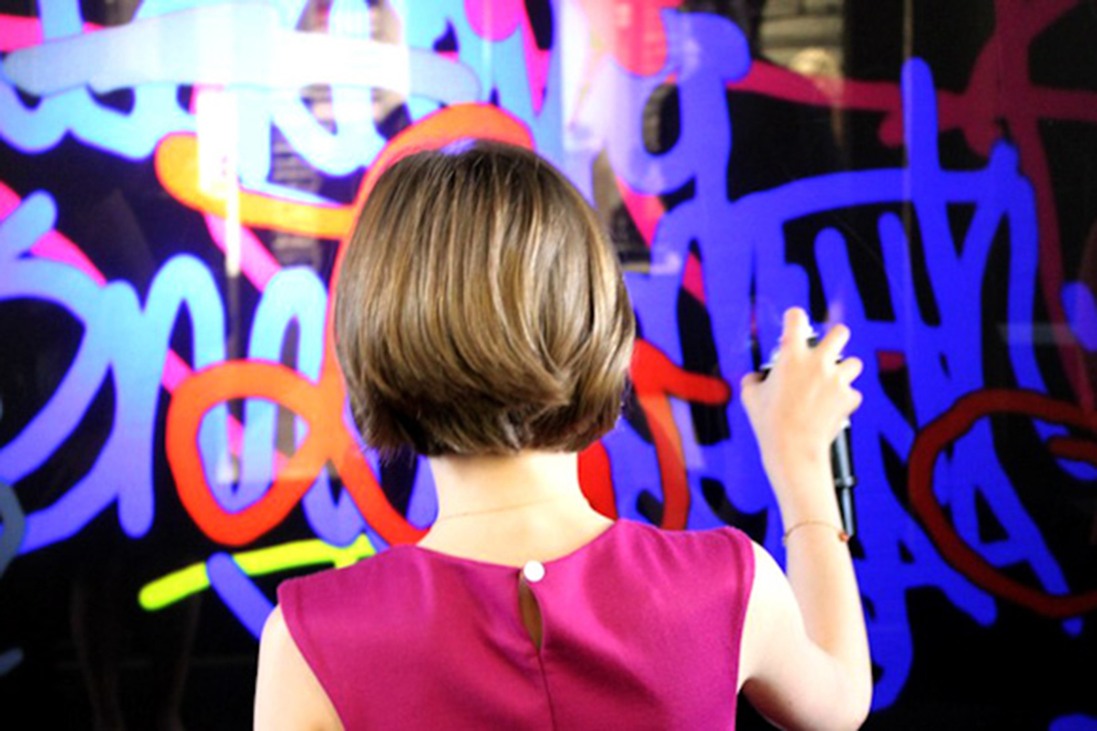 Une femme faisant des graffitis sur le mur interactif