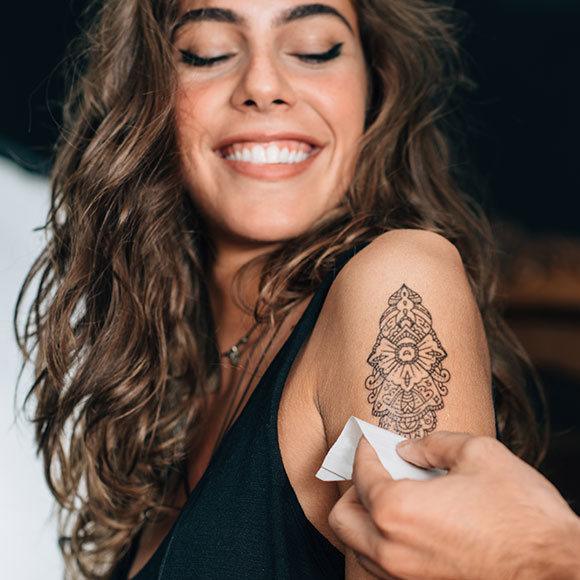 Pose d'un tatouage éphémère sur le bras d'une invité lors d'une soirée