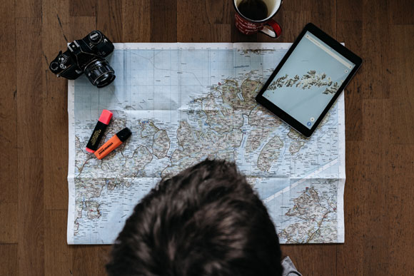 participant à une chasse au trésor en ligne, regardant une carte papier et sur tablette tactile