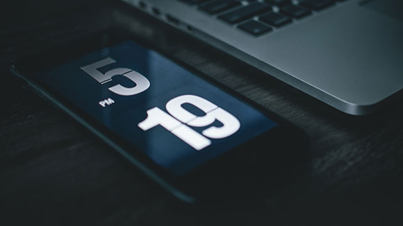 téléphone avec timer posé sur un bureau à côté d'un ordinateur